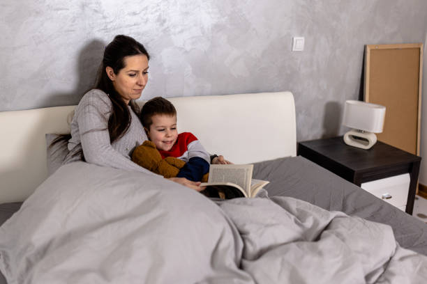 istock A young mother is reading a book with her son in a bedroom. 1612332194