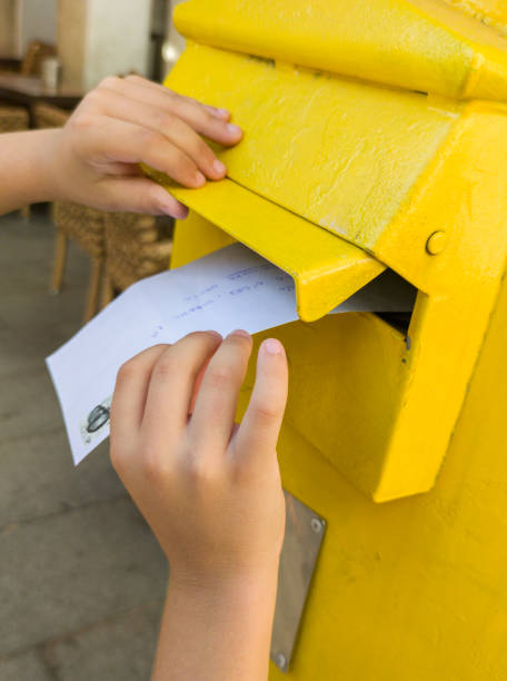 istock Boy putting a letter in the spanish yellow traditional mailbox 1612375932
