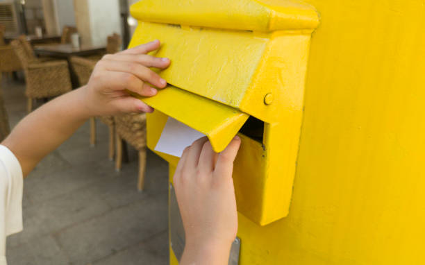 istock Boy putting a letter in the spanish yellow traditional mailbox 1612375938
