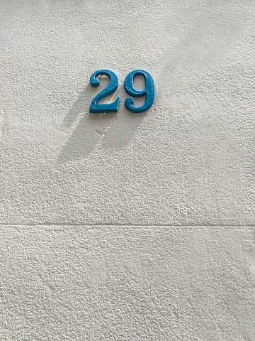 House number 29, blue painted iron over wall. Houses with personality concept