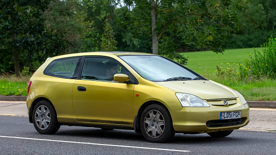Milton Keynes,UK - Aug 13th 2023:  Gold 2001 Honda Civic car driving on an English country road.