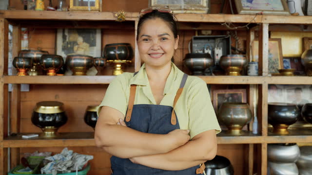 A smiling handicraft shop owner with arms folded takes pride in his small business in Bangkok.