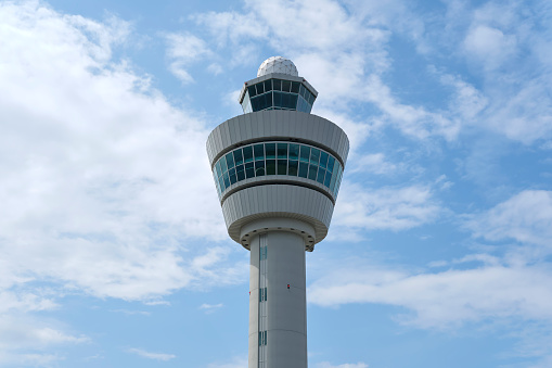 Air control tower on an airport in the Netherlands against a blue sky with clouds