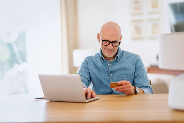 istock Man sitting at home and using credit card and notebook and paying online 1612419921