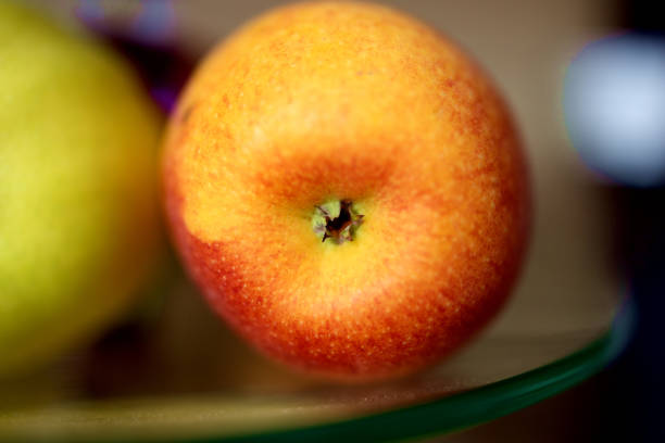 A red apple behind in a glass plate