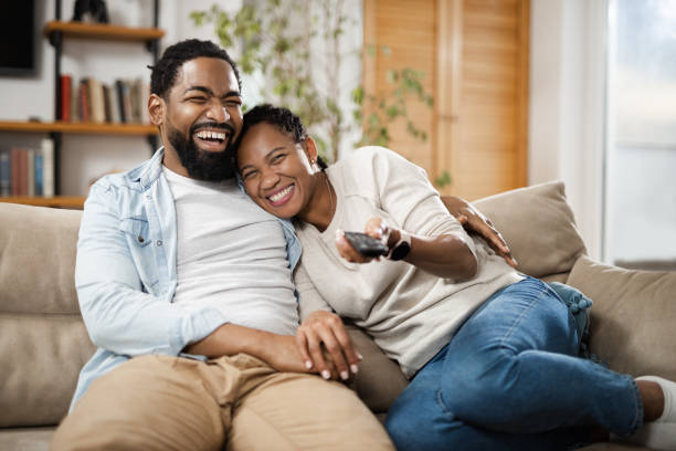 istock Black couple watching TV while relaxing on the sofa at home 1612438222