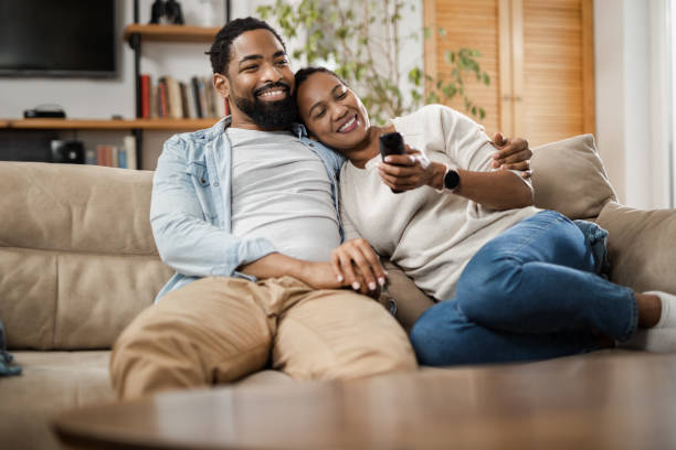 istock Black couple watching TV while relaxing on the sofa at home 1612443478