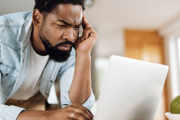 istock Worried black man working on laptop at home 1612450745
