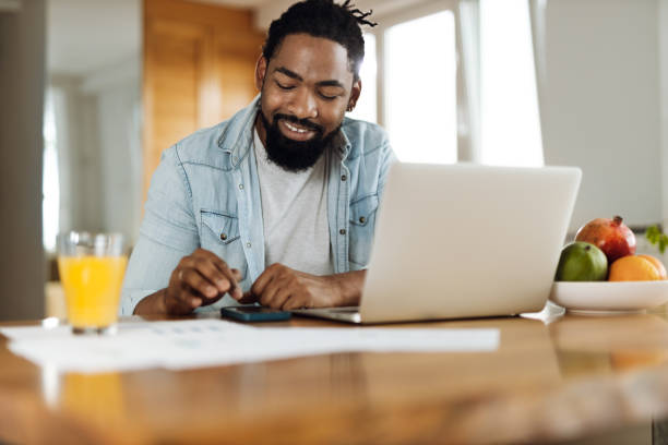 istock Young black man  paying his  bills over laptop at home 1612457966