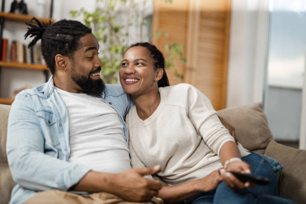 istock Young African American couple talking while watching TV at home 1612468875