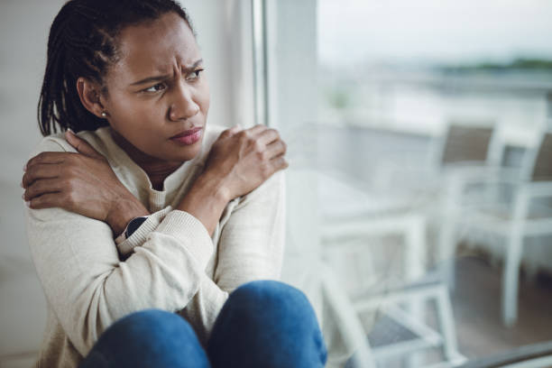 istock Pensive black woman by the window at home 1612476367