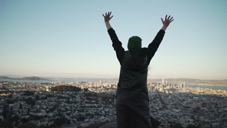 Teen girl raising her hands on Twin Peaks in San Francisco in sunset