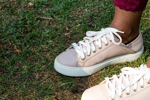 Close-up of woman wearing casual new sneakers with white shoelaces