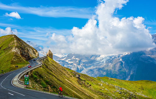 Male model aged 25-30. Red t-shirt helmet overlooking the road and nature view from a high position. Leaning on bike