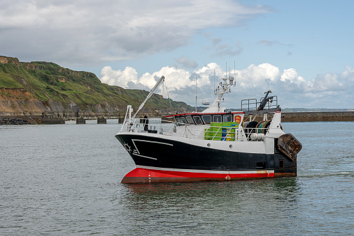 Port-en-Bessin-Huppain, France - 07 24 2023: View of a fishing boat entering the harbor