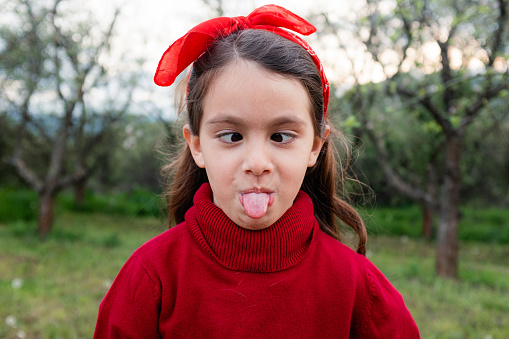 Little girl having fun making facial expressions and humor  while posing in nature