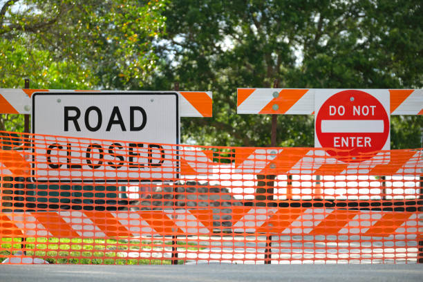 istock Road closed at construction site with protective fence barrier 1612631273