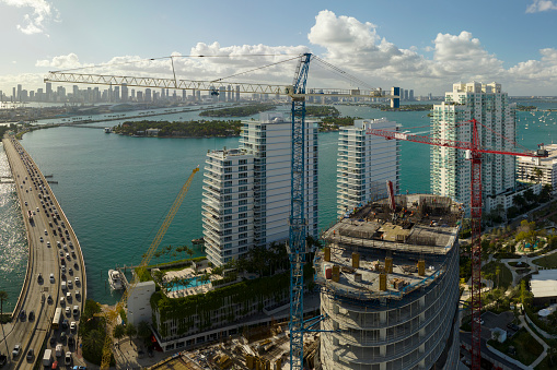 Aerial view of new developing residense in american urban area. Tower cranes at industrial construction site in Miami, Florida. Concept of housing growth in the USA. Miami, USA - May 8, 2023.