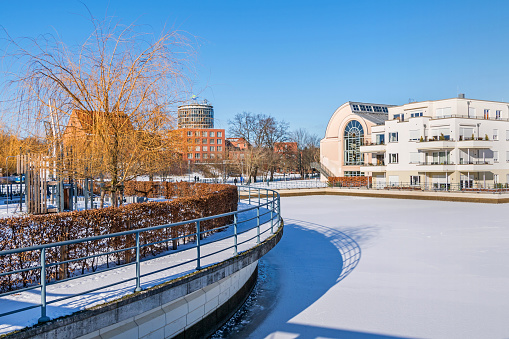 Berlin, Germany - February 12, 2021: Frozen Harbor basin Tegeler Hafen with the buildings of the Humboldt Library and the clinic Medical Park Humboldtmuehle