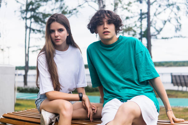 istock two young people are sitting on a bench in a coastal park 1612754667