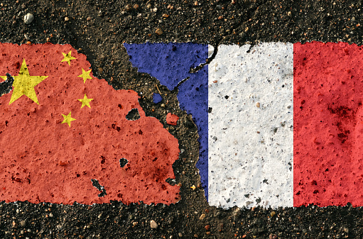 On the pavement there are images of the flags of China and France, as a symbol of the confrontation between the countries. Conceptual image.