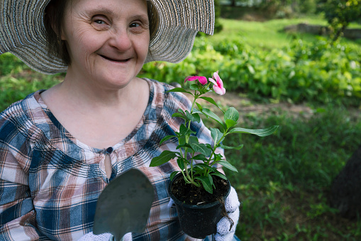Portrait of a happy woman with Down Syndrome ready to planting flowers. Gardening.