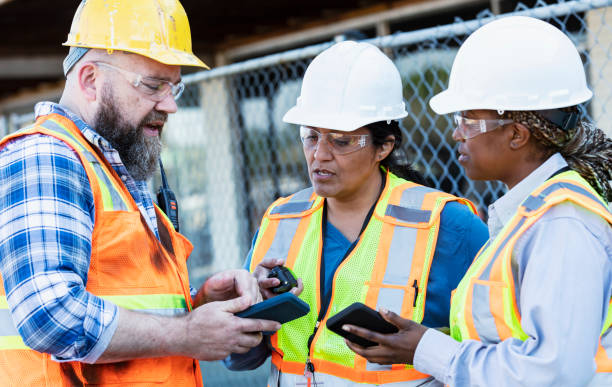 istock Diverse construction workers meet, look at mobile phone 1612927113