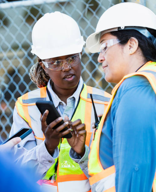 istock Two female construction workers look at mobile phone 1612927114