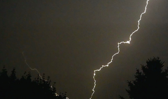 Bolt of lightning over the trees during a storm.