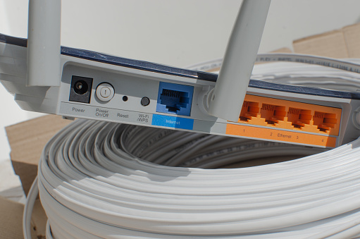 Close-up detail of a modern Wi-Fi router, with multiple inputs and ports for cable connections, representing internet technology and connections