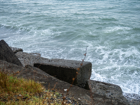 Old blocks of fortifications of the coast. Concrete structures on the shore. Protection against storms, waves and avalanches. wave movement