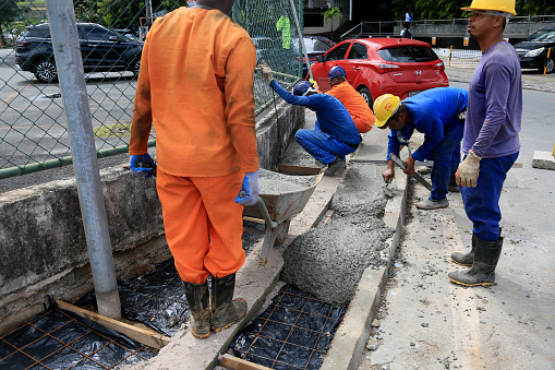 salvador, bahia, brazil - august 11, 2023: workers are seen building a concrete sidewalk of a street in the city of Salvador