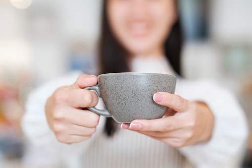 Close-up of barista serving coffee at cafeteria. Barista hands holding a coffee cup, small business owner, food and drink industry concept. Coffee Business Concept