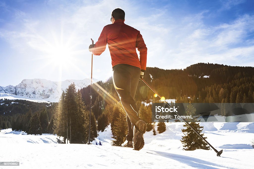 Soleil brille sur un homme faire du ski de fond dans les montagnes. - Photo de Paire de skis de fond libre de droits