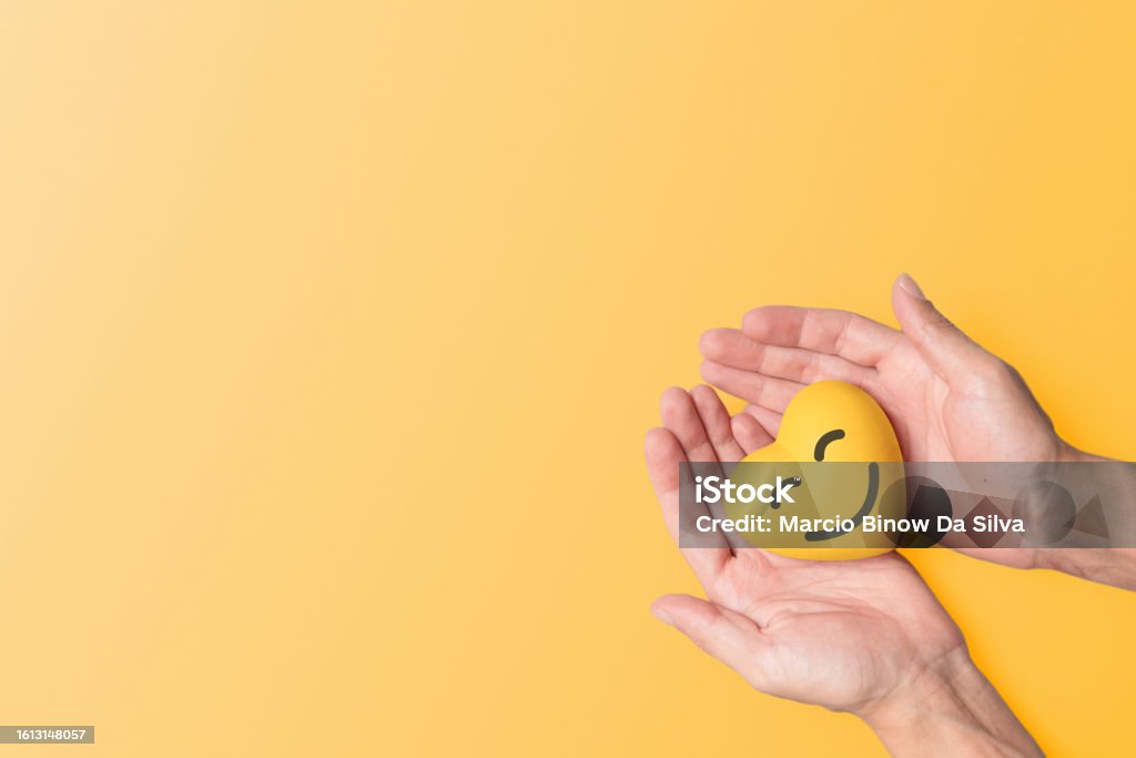 Yellow September: mental health Hands tenderly holding a yellow resin heart against a matching yellow background, symbolizing mental health awareness and the significance of September Yellow, a month dedicated to mental well-being and suicide prevention Yellow Stock Photo