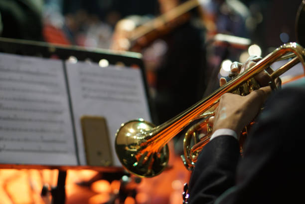 istock Hands playing trumpet orchestra with note sheet on stage. 1613152331