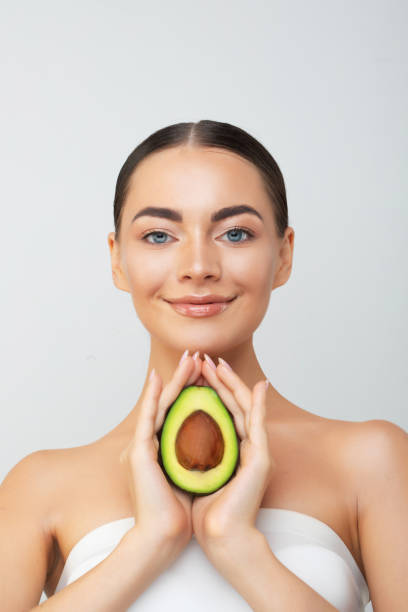 istock Beautiful young woman with fresh avocado on light background. 1613191019