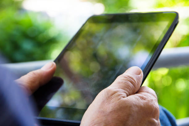 istock Senior man sitting outside reading E-book on his tablet. 1613231636