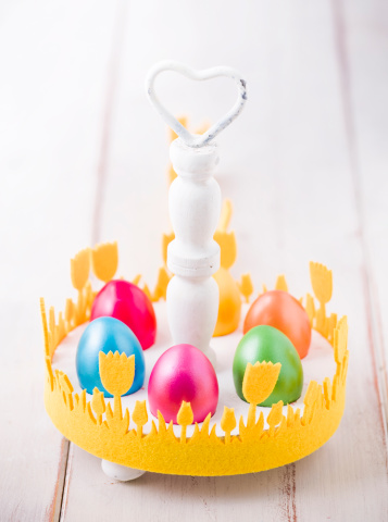 Woman decorating tree with easter toys, colorful eggs, decorated fresh green tree with coloring eggs, Happy Easter holiday. High quality photo