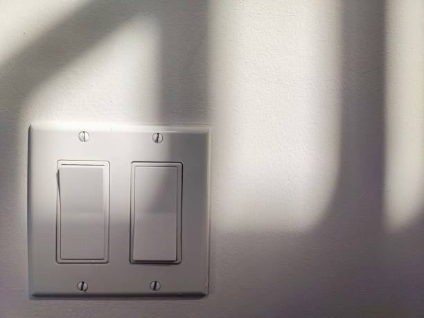istock Two switches on the wall under the late afternoon sunlight. A beautiful window shadow is cast on the wall. 1613238922