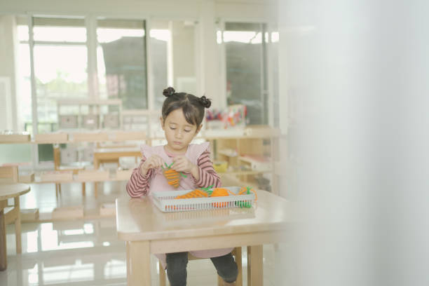 istock Preschool mixed girl threading a carrot shaped sewing card 1613281128