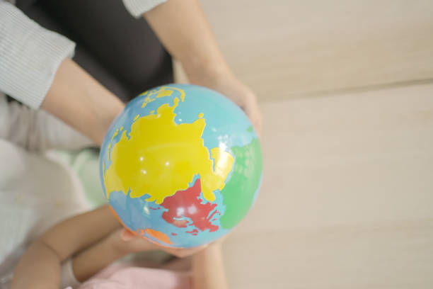 little girl holding globe in her arms, eyes closed, against blue sky