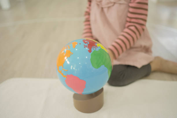 дошкольница изучает карту мира с моделью глобуса в школе монтессори и домашнем обучении - spinning classroom indoors exercising стоковые фото и изображения