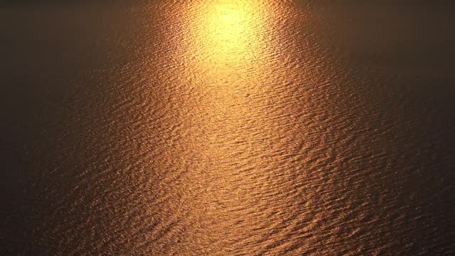 Very high aerial view of orange red sunset lights reflecting on the sea