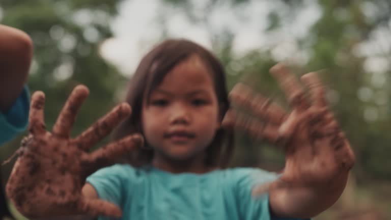 Portrait of young girl showing dirty hands while standing in forest scene.