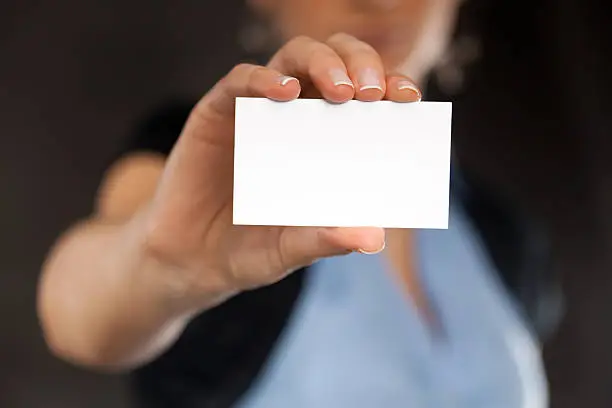Close-up of a blank business card in businesswoman's hand. Dark background. You can put your text.