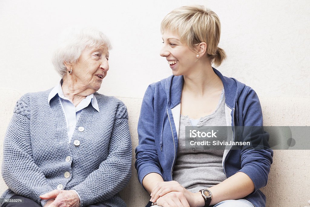 Giovane donna e una donna anziana sorridente e parlare - Foto stock royalty-free di Terza età