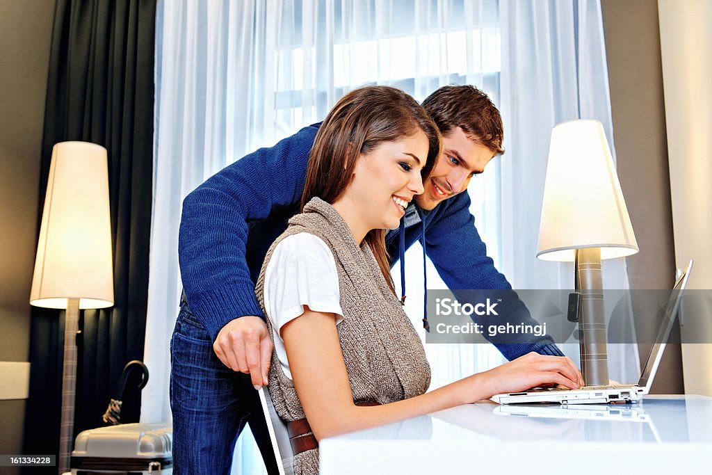 Giovane coppia utilizzando il computer in una camera d'hotel - Foto stock royalty-free di 20-24 anni