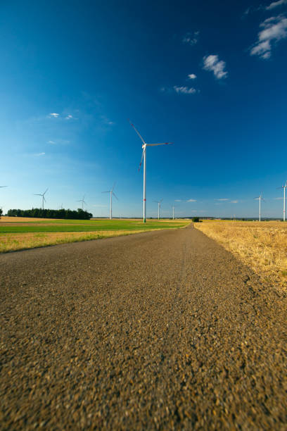 istock Windmills set along the road on blue sky background.Wind generators landscape. Natural renewable clean eco energy. Alternative energy sources.Environmentally energy source. 1613345495