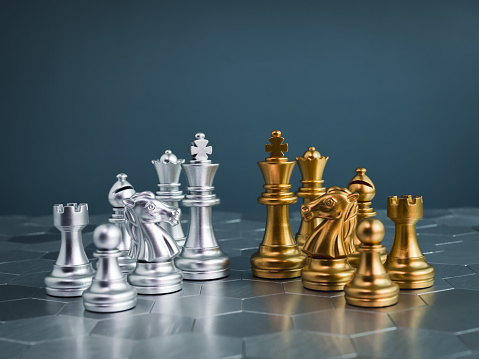 Set of golden and silver chess pieces element, king, queen rook, bishop, knight, pawn standing on hexagon pattern chessboard on blue background. Competition, game, war, emulation and planning concept.